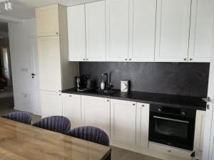 a kitchen with white cabinets and a table with chairs at Apartament Latarnik- BIG in Gąski