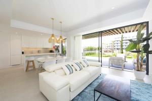 a living room with a white couch and a kitchen at Espectacular bajo con jardín en 1ª línea de playa in Torremolinos