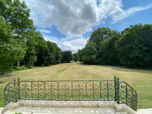 una valla metálica en un campo con árboles en Le château de Courbouzon, en Courbouzon