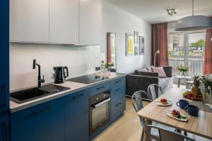uma cozinha com armários azuis e uma sala de estar em Barska 69 Apartments na Cracóvia