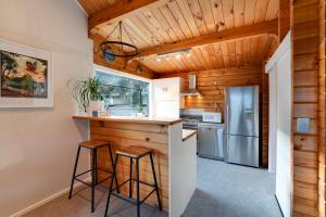 una cocina con techos de madera y un bar con taburetes en Alpine Hide Away - 3 Bedroom, en Closeburn