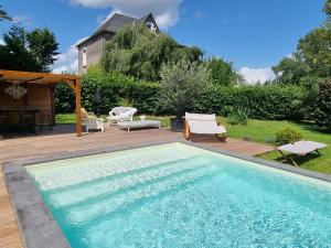 una piscina en un patio con mesa y sillas en VILLA MURA gite luxe avec piscine et spa campagne et grand air nouvelle Aquitaine Corrèze en Neuvic