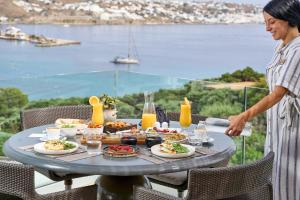 a woman standing in front of a table with food at Mykonos Princess Hotel in Agios Stefanos