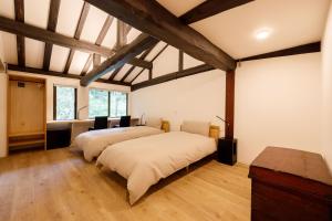 two beds in a large room with wooden ceilings at Denpaku Komatsu in Komatsu