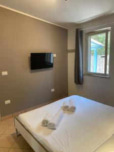 a bedroom with a bed with towels and a flat screen tv at Quirino Residence in Gaeta