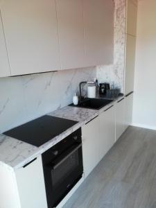 a kitchen with white cabinets and a black stove top oven at Apartament Latarnik- Yellow in Gąski