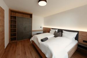 um quarto com uma grande cama branca e pisos em madeira em Johann Apartments em Neustift im Stubaital