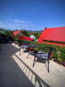 毛茛的住宿－公寓Ruzica旅館，一个带两把椅子和一张桌子的庭院和红色屋顶
