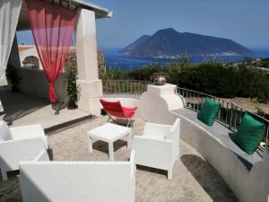 un patio con sillas blancas y vistas al océano en Sweet Home, en Quattro Pani