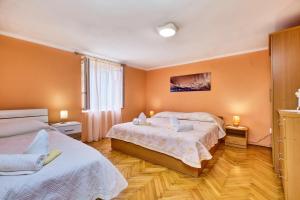 two beds in a room with orange walls and wooden floors at Apartments Ljubica in Veli Lošinj