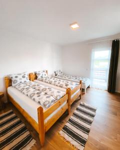 two beds in a room with wooden floors and a window at Pensiunea Maris, Maguri, Maguri-Racatau in Bogdăneşti