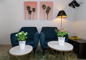 ein Wohnzimmer mit einem blauen Sofa und 2 Tischen mit Blumen in der Unterkunft Triana Pelay in Sevilla