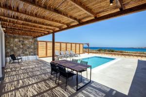 een patio met een tafel en stoelen en een zwembad bij Cato Agro 2, Seafront Villa with Private Pool in Karpathos