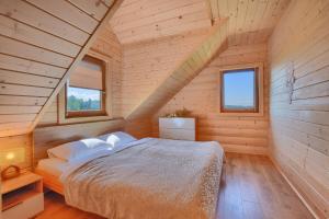 een slaapkamer met een bed in een houten huis bij Domki inNatura in Istebna