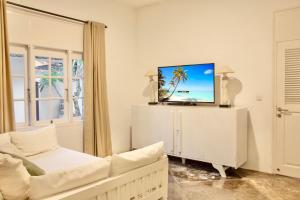 a living room with a white couch and a tv at Villa EMMA | heart of Seminyak | 350m Beach in Seminyak