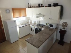 La cuisine est équipée de placards blancs et d'un réfrigérateur blanc. dans l'établissement Cyking Apartment 103 postcode 8046, à Paphos