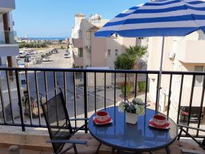 a table and chairs on a balcony with an umbrella at Cyking Apartment 103 postcode 8046 in Paphos