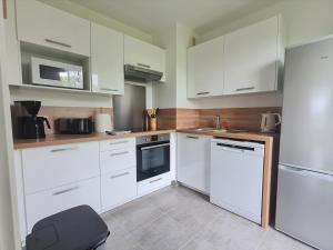 uma cozinha com armários brancos e um frigorífico branco em Grand Appartement Dreams em Montévrain