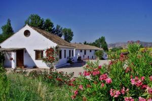 una casa blanca con flores delante en Fincaretama Farmhouse Apartment Ronda, en Ronda