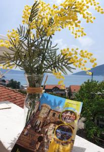 un vaso pieno di fiori gialli, seduto accanto a una rivista. di R&S Apartments a Herceg-Novi