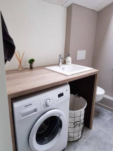 een badkamer met een wasmachine en een wastafel bij La Maison Coco in Honfleur