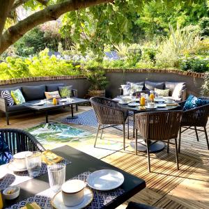 una mesa y sillas en un patio con mesa en VILLA DU CEDRE Honfleur, en Honfleur