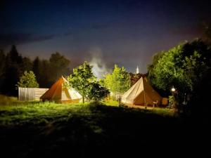 een groep tenten in een veld 's nachts bij Pokoje u Basi Glamping Mikołajki in Mikołajki