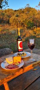 uma garrafa de vinho e um copo numa mesa de madeira em Pousada Canto da Lua - charme e vista incrível em Carrancas