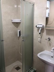 a shower with a glass door next to a sink at Grand Victoria Hotel in Kyrylivka