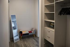1 dormitorio con armario con espejo y taburete en Rundale Solstice Apartment, en Pilsrundāle