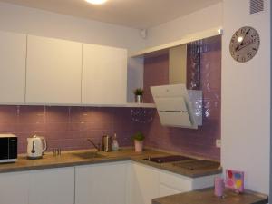 a kitchen with white cabinets and a clock on the wall at Apartament w Pucku in Puck