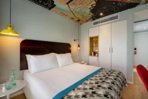 Hotel 75 by Prima Hotels في تل أبيب: غرفة نوم بسرير ابيض كبير وكرسي احمر