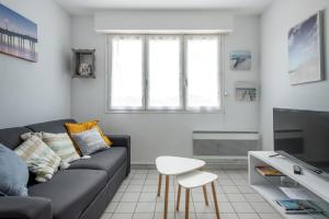 uma sala de estar com um sofá e uma mesa em Appartement dos à la marina - Proche de la plage em Courseulles-sur-Mer