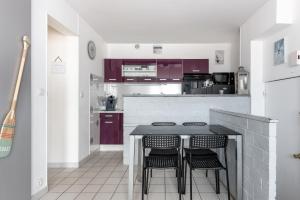 uma cozinha com armários roxos e uma mesa com bancos em Appartement dos à la marina - Proche de la plage em Courseulles-sur-Mer
