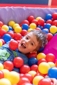 a young boy swimming in a pool of balls at Hotel Columbia in Marina Romea