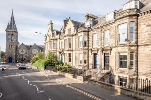 a street in front of a building with a church at Skye Sands - Strathtyrum Patio Residence - St Andrews in St Andrews