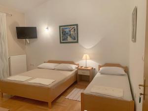 two beds in a small room with a tv at Pansion Villa Bubalo in Mostar