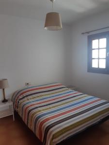 un letto con una coperta a righe in una stanza con finestra di La Laja 9 a Playa Blanca