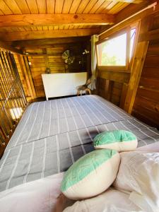 Una cama en una cabaña de madera con almohadas. en Banana Cottage Ecolodge & Spa, en Le Gosier