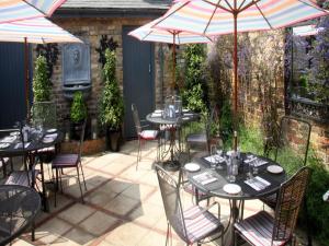 un patio con tavoli, sedie e ombrelloni di Gilbey's Bar, Restaurant & Townhouse a Windsor