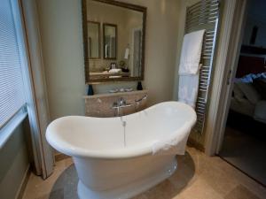 uma banheira branca na casa de banho com um espelho em Gilbey's Bar, Restaurant & Townhouse em Windsor