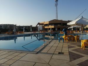 a swimming pool with chairs and tables and an umbrella at 52H Green leaves Village, families & couples only in Dawwār Abū Duray‘ah ‘Abd al Karīm