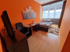 un soggiorno con pareti arancioni, scrivania e sedia di Pokoje Gdynia Orłowo a Gdynia