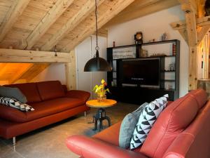 uma sala de estar com dois sofás de couro e uma televisão em "alti Post" zentralgelegene, stilvolle Dachwohnung em Täsch