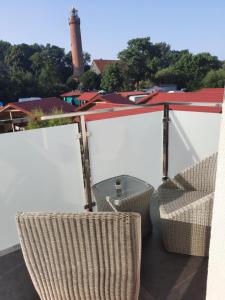 a balcony with chairs and a lighthouse in the background at Apartament Latarnik- STANDARD in Gąski