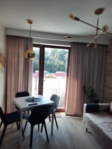 een woonkamer met een tafel en stoelen en een bank bij Apartament Latarnik- STANDARD in Gąski