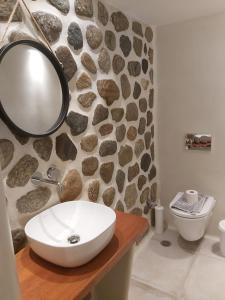 a bathroom with a sink and a rock wall at Anna Studios in Agios Prokopios