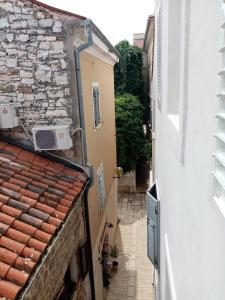 an alley between two buildings with a stone wall at San Eleuterio Guesthouse in Poreč