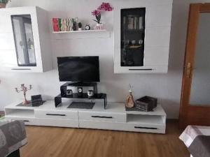 una sala de estar con TV en un centro de entretenimiento blanco en Haus Enzian - Apartment Gerlitzen, en Kanzelhöhe