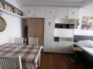 a kitchen with white cabinets and a table in a room at Haus Enzian - Apartment Gerlitzen in Kanzelhöhe